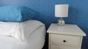 a bed with a white night stand with a lamp on it at Bickersbed in Amsterdam