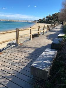 a wooden boardwalk next to a beach with a fence at Magnifique T2 en bord de mer in Le Lavandou