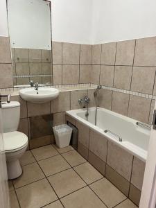 a bathroom with a sink and a tub and a toilet at L’Escalier Cabanas 510 in Amanzimtoti +6 photos