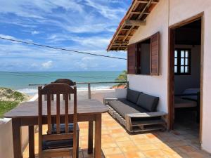 a patio with a table and chairs and the ocean at Pousada Casa Feliz Maxaranguape in Maxaranguape