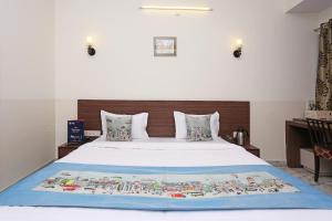 1 dormitorio con 1 cama blanca grande y cabecero de madera en Hotel Maan's Heritage, en Jaipur