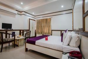 a bedroom with a bed and a desk and a television at Hotel Surya Residency in Ameerpet