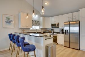 a kitchen with white cabinets and blue bar stools at Luxury Galveston Retreat - Walk to Pirates Beach! in Galveston