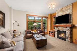 ein Wohnzimmer mit einem Kamin und einem TV in der Unterkunft Luxury Ski In, Ski Out 3 Bedroom Mountain Resort Vacation Rental In The Heart Of Snowmass Base Village in Aspen