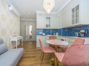 a kitchen with a table and pink chairs in a room at Flatbook - City Center Apartments Granaria II in Gdańsk