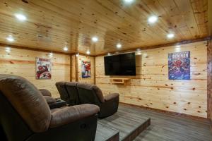 a living room with two chairs and a flat screen tv at Pool and Game Room in Stunning Mountain Cabin in Pigeon Forge