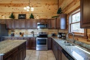 a kitchen with wooden cabinets and a stove top oven at Pool and Game Room in Stunning Mountain Cabin in Pigeon Forge