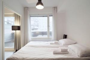 a white bedroom with two beds and a window at Norden Homes Castle Harbour Apartment in Turku