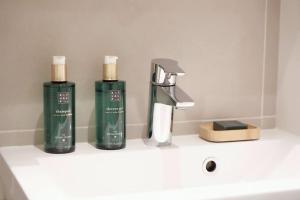 two bottles of soap and a faucet on a bathroom sink at Norden Homes Castle Harbour Apartment in Turku
