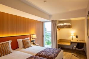 Cette chambre comprend un lit, un bureau et une fenêtre. dans l'établissement Hotel 3K Porto Aeroporto, à Maia