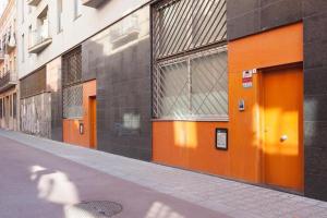 an empty street with orange doors on a building at Vale Beach in Barcelona