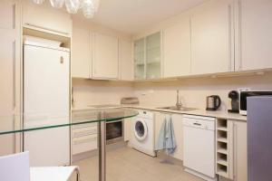 a kitchen with white cabinets and a washing machine at Vale Beach in Barcelona