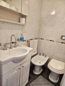 a white bathroom with a sink and a toilet at Obelisco Apartment in Buenos Aires