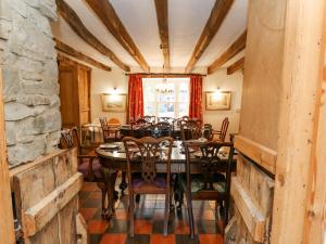 Cringoed House في أبيريرون: غرفة طعام مع طاولة وكراسي وجدار حجري