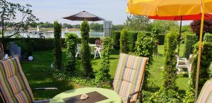 un patio con mesa, sillas y sombrilla en Gästehaus Am See en Xanten