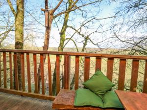 a wooden bench with two green pillows on a deck at Tree House in Aberaeron