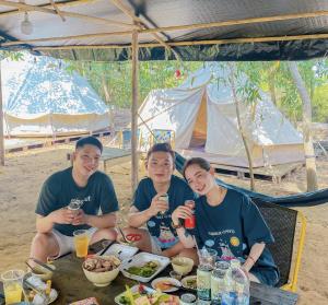 Un groupe de trois personnes assises à une table avec de la nourriture dans l'établissement SAY Camp Forest, à Cần Giờ