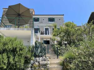 a house with stairs leading up to a building with an umbrella at Holiday Home Aria in Podgora