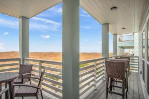 porche con sillas y mesas y vistas a la playa en BeachHouse Bliss, en Padre Island