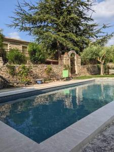 a swimming pool in front of a house with a tree at Mas dans les lavandes in Ménerbes