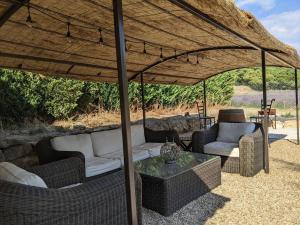 eine Terrasse mit Sofas und einem Tisch unter einem Sonnenschirm in der Unterkunft Mas dans les lavandes in Ménerbes