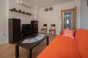 uma sala de estar com um sofá laranja e uma mesa de centro em Apartamento Malibu Cadiz playa em Cádis