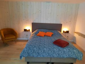ein Schlafzimmer mit einem Bett mit orangefarbenen Kissen und einem Stuhl in der Unterkunft Le Grand Ravel in Weismes
