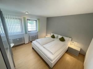 een slaapkamer met een bed met witte lakens en groene kussens bij Ferienwohnung Antonia am Staufenpark in Oberstaufen