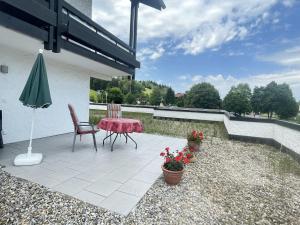 een terras met een tafel, stoelen en een parasol bij Ferienwohnung Antonia am Staufenpark in Oberstaufen