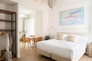 a white bedroom with a bed and a table at Mylu Suites by Puerta Catedral in Seville