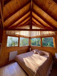 a bedroom with a bed in a room with windows at Apart Hotel Altos de Antilhue in Villa La Angostura