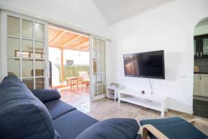 Una sala de estar con un sofá azul y un televisor. en Sunset Bungalow, en San Bartolomé