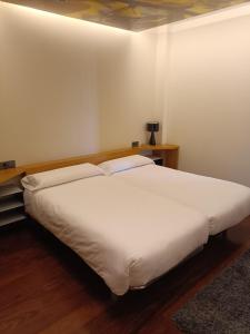 Cama blanca grande en habitación con suelo de madera en Hotel Raíz en Roa