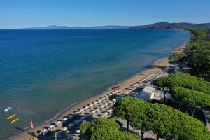- une vue aérienne sur une plage avec des parasols et des chaises dans l'établissement Golf Hotel Punta Ala, à Punta Ala