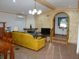 uma sala de estar com um sofá amarelo e uma televisão em Villa Mónica em Orihuela