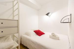 ein weißes Schlafzimmer mit einem Bett mit einem roten Kissen in der Unterkunft Lavie Maison large comfy flat in Bordeaux