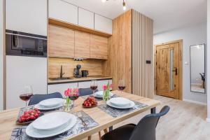 a kitchen and dining room with a wooden table and chairs at Dziwnów River Side Apartment with Balcony by Renters Prestige in Dziwnów