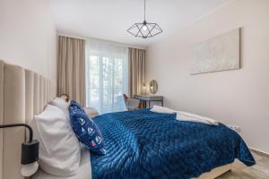 a bedroom with a bed with a blue comforter at Dziwnów River Side Apartment with Balcony by Renters Prestige in Dziwnów