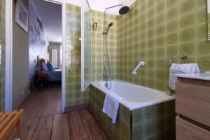 La salle de bains est pourvue d'une baignoire et d'une douche en verre. dans l'établissement Rougetomette, à Nîmes