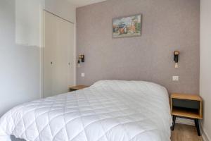 a bedroom with a white bed and two night stands at Coquet appartement a 300 m du port du Pouliguen in Le Pouliguen