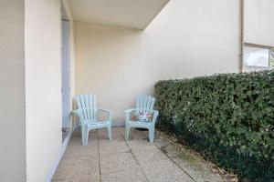 two chairs sitting on a patio next to a hedge at Coquet appartement a 300 m du port du Pouliguen in Le Pouliguen