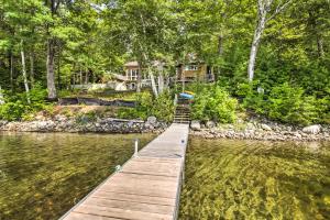 a dock in a lake with a house in the background at Beautiful Embden Pond Cabin with Dock and Kayaks! in Embden