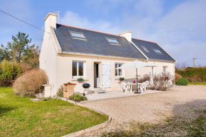a white house with a table and chairs at Vacances en famille ou entre amis a Penmarch in Penmarcʼh