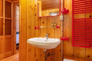 La salle de bains est pourvue d'un lavabo et d'un volet rouge. dans l'établissement Il Salice by Wonderful Italy, à Bellagio