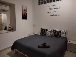 una camera da letto con un letto con una coperta nera e cuscini di Alessi Suites & Studio a Mazzarino