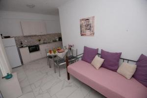 a living room with a pink couch and a kitchen at Filoxenia Apartments Corfu Rose in Alepou +14 photos