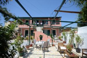 a patio with a table and chairs and a building at Filoxenia Apartments Corfu Rose in Alepou