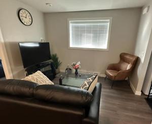 sala de estar con sofá, mesa y reloj en Cozy BSMT Apt w/2BR+Disney+ Nflx, en Saskatoon