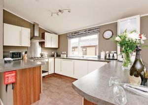 a kitchen with white cabinets and a vase of flowers at Ashby Woulds Lodges And Spa in Moira