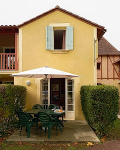 a table with chairs and an umbrella in front of a house at Maison de vacances pour détente dans résidence familiale avec prêt de vélos in Monflanquin
